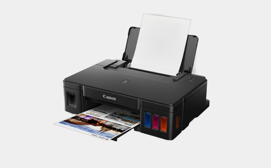 Canon PIXMA ink tank printer with visible cyan, magenta and yellow ink tanks printing a colour photo